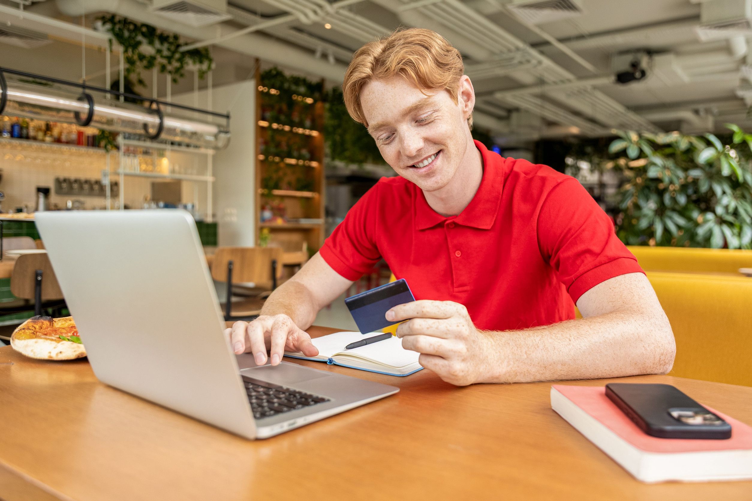 A Smiling Young Student Paying Online From A Laptop