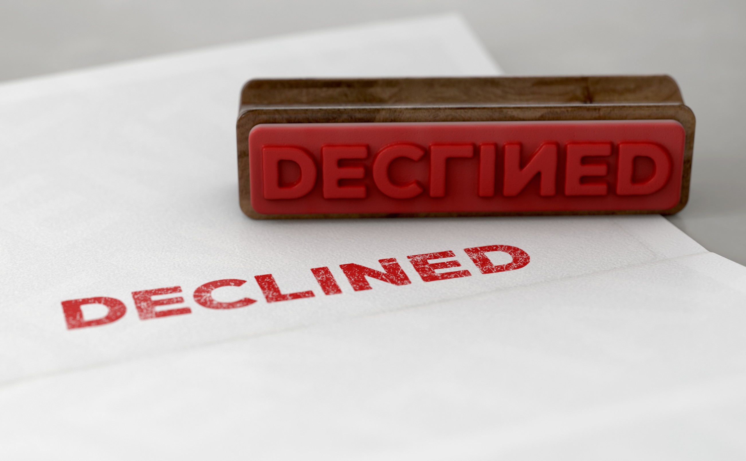 A Wooden Stamp With Embossed Text Stamping The Word Declined On A Form