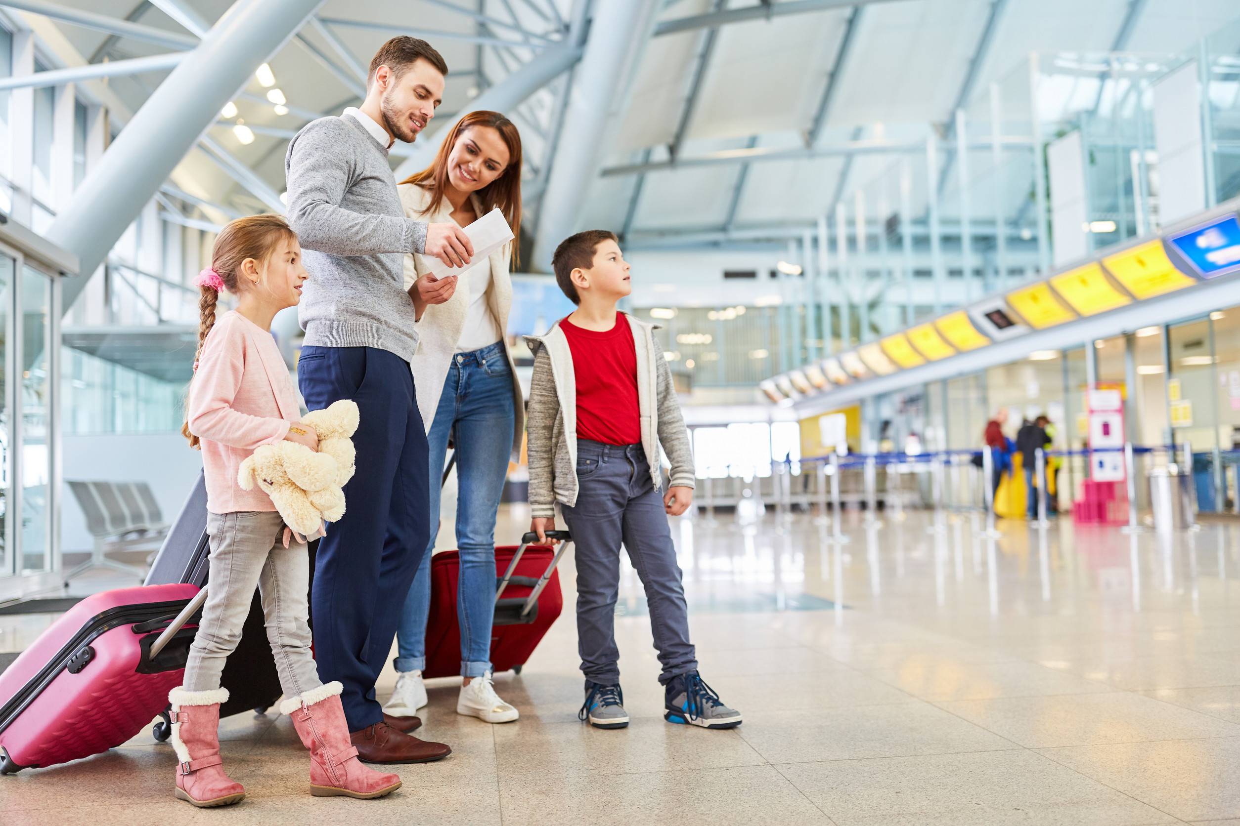 Famille et enfants avec bagages dans le terminal de l'aéroport, voyageant ensemble en vacances.