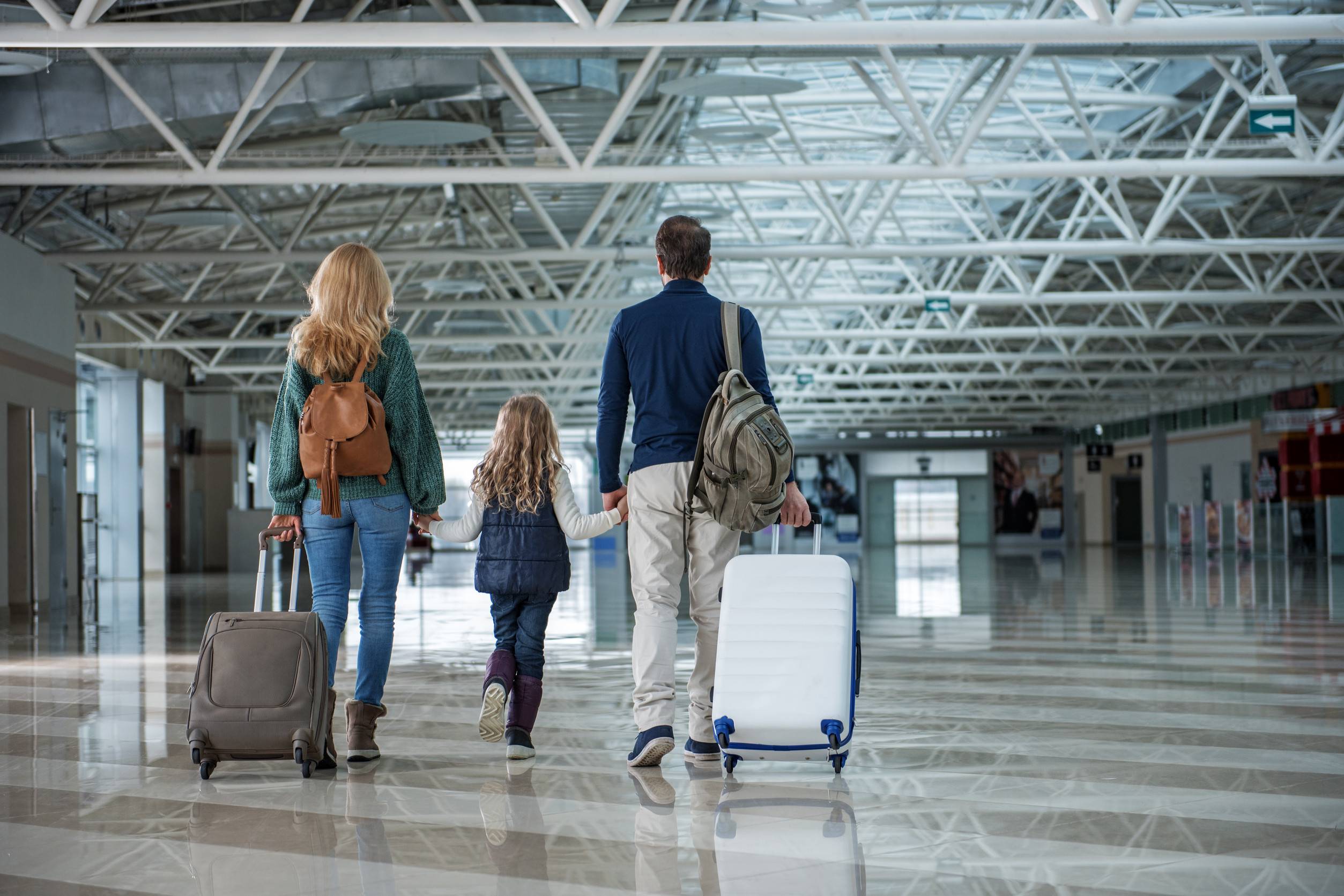 Mutter, Vater und ihre kleine Tochter kommen nach langer Reise am Flughafen an.