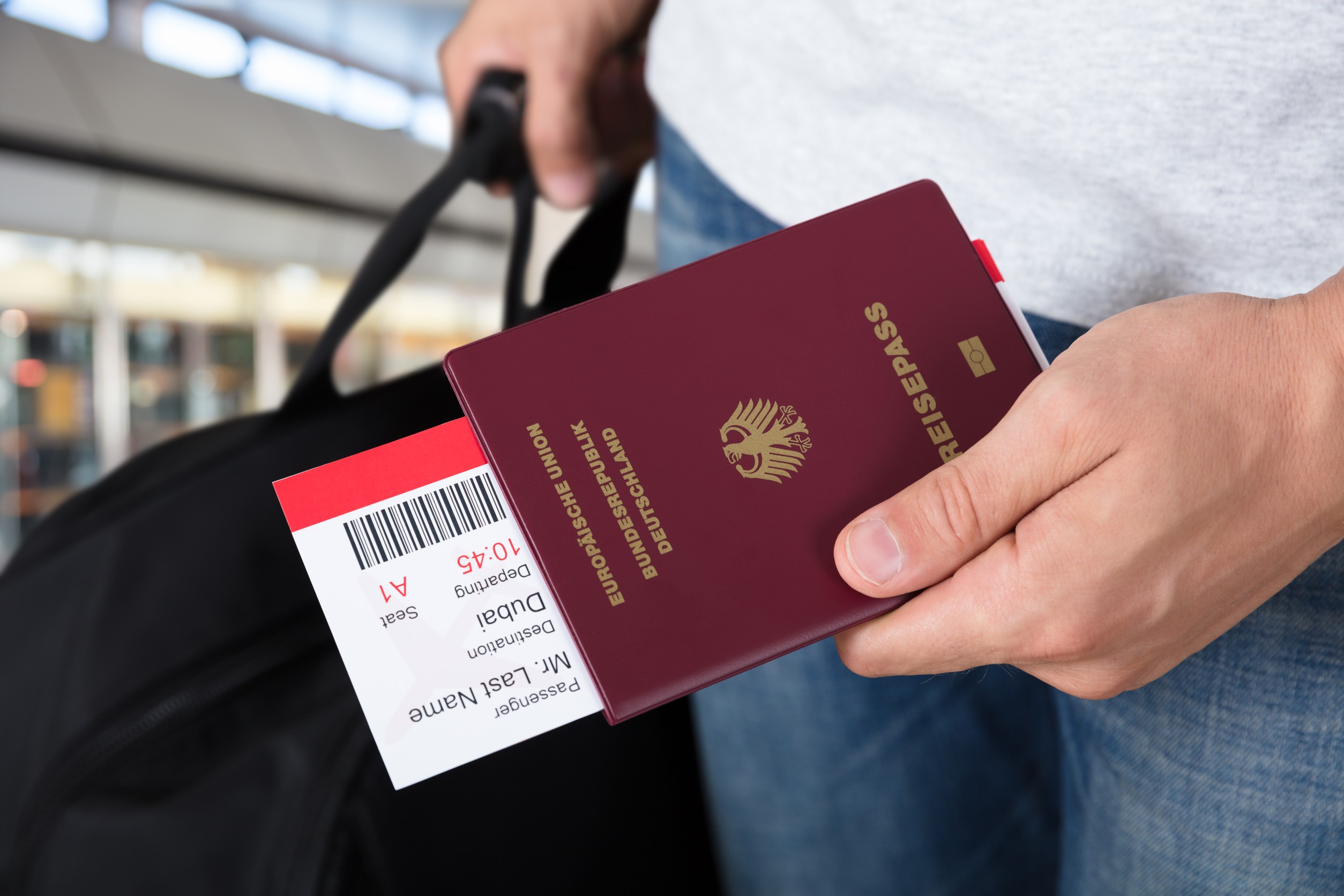 Personne tenant un passeport et une carte d'embarquement avec un bagage à l'aéroport