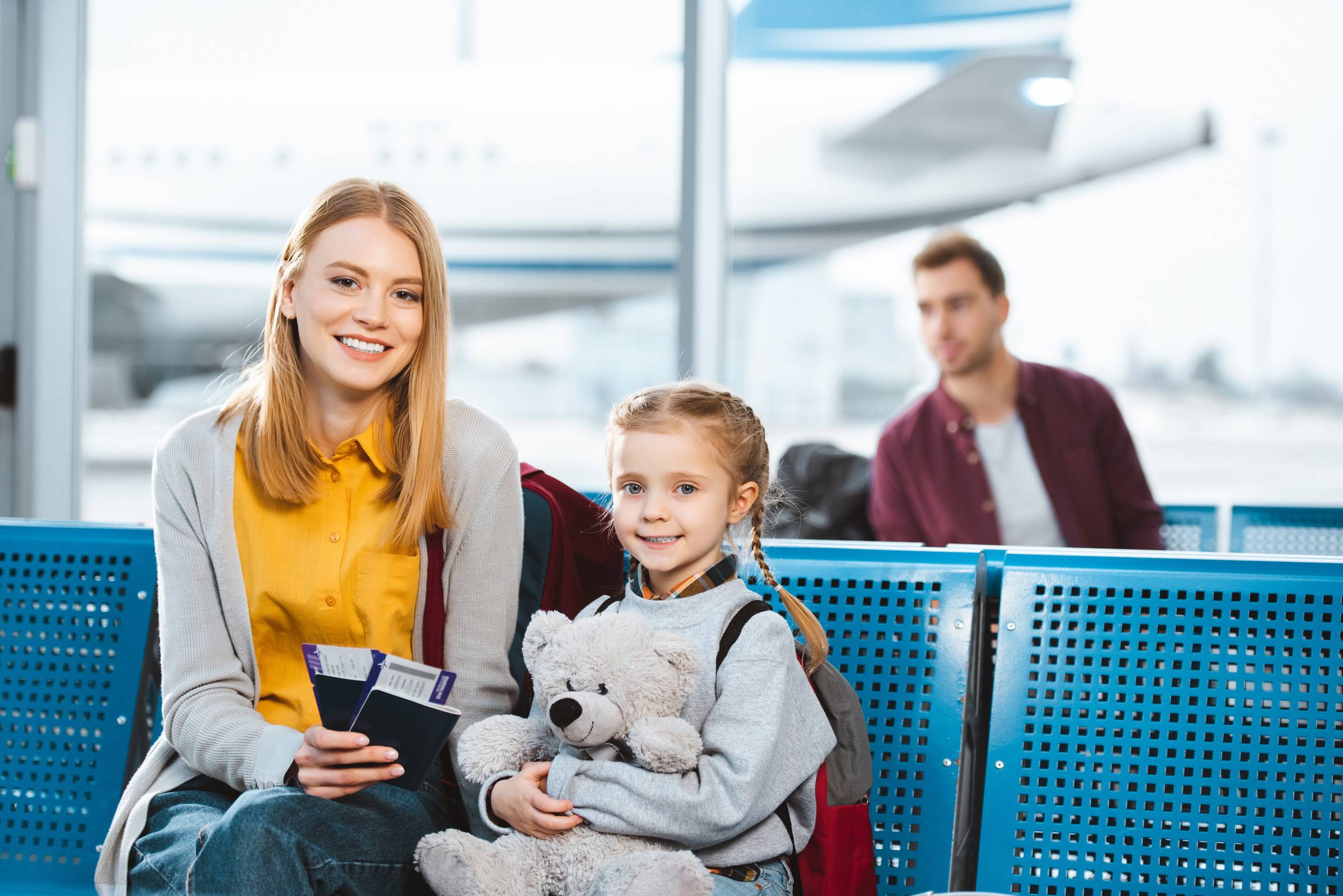 Selektiver Fokus: Mutter mit Reisepässen und Flugtickets in der Hand und lächelnd neben Tochter
