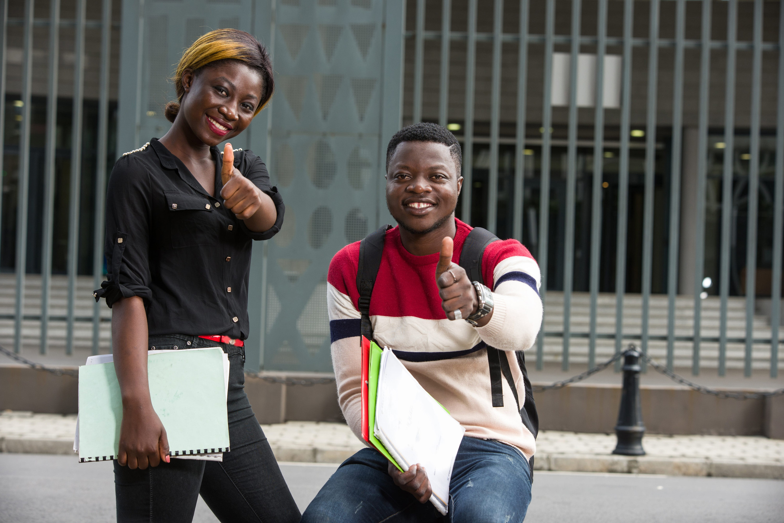 Students holding books outside a study institution