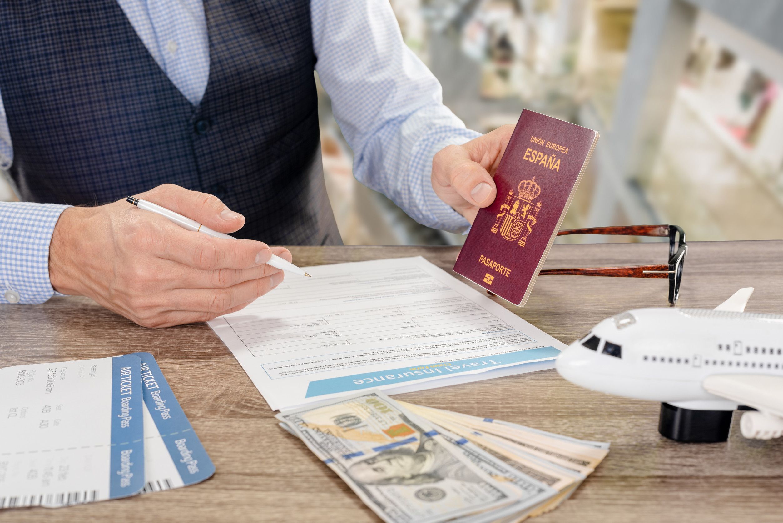 Jeune homme d'affaires muni d'un passeport international et d'un billet d'avion, remplissant un formulaire d'assurance avant le voyage